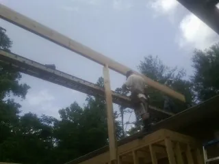 Carpenter setting a ridge beam over a new addition frame — Ice Dam Removal by Roofing Brothers in Irene