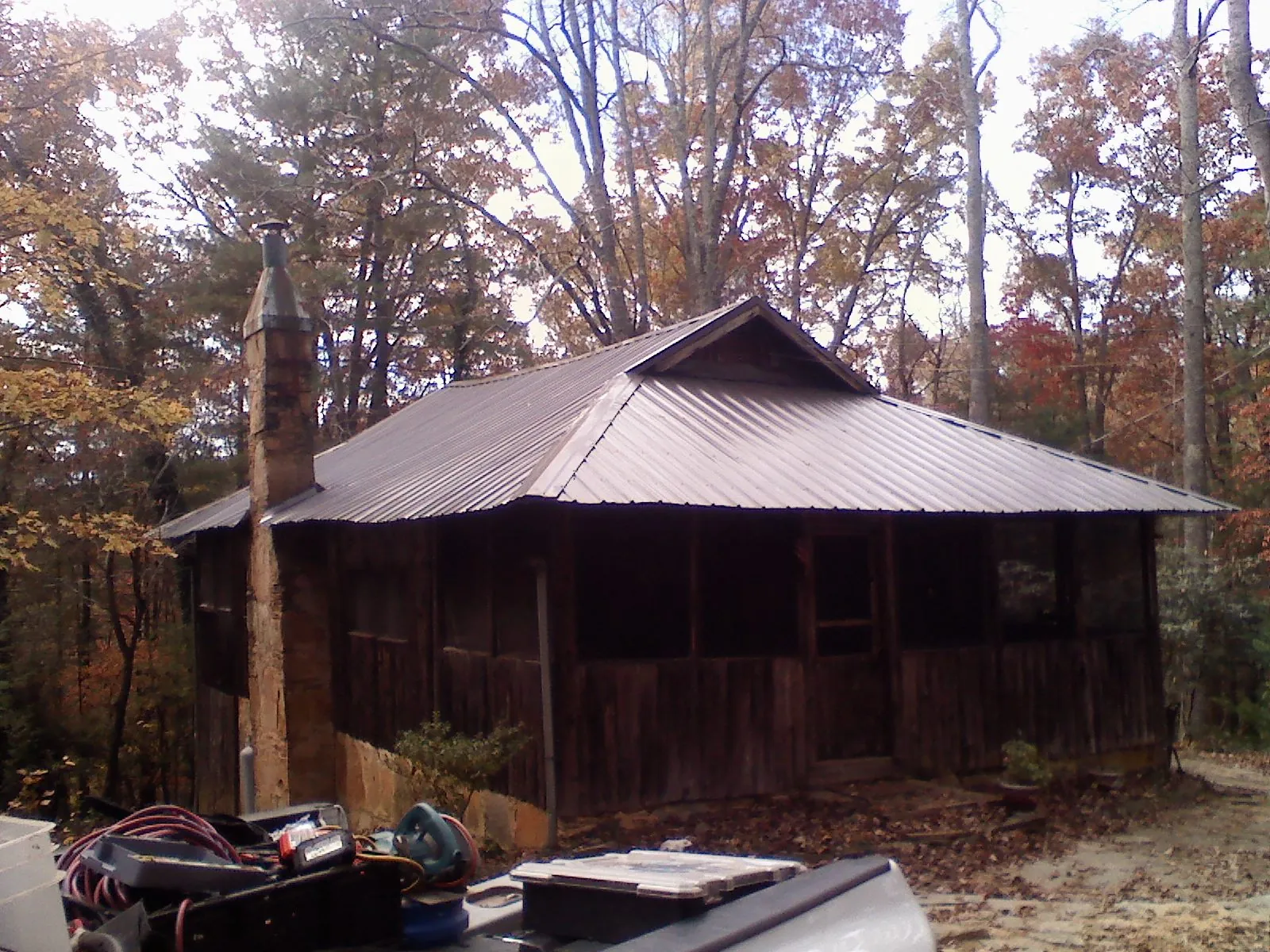 Brown metal hip roof on an old cabin with a stone chimney in Irene
