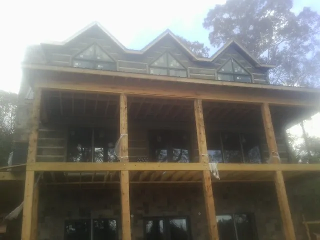 Dormers and porch framing on a large log home under construction — Roof Coating work by our crew in Irene