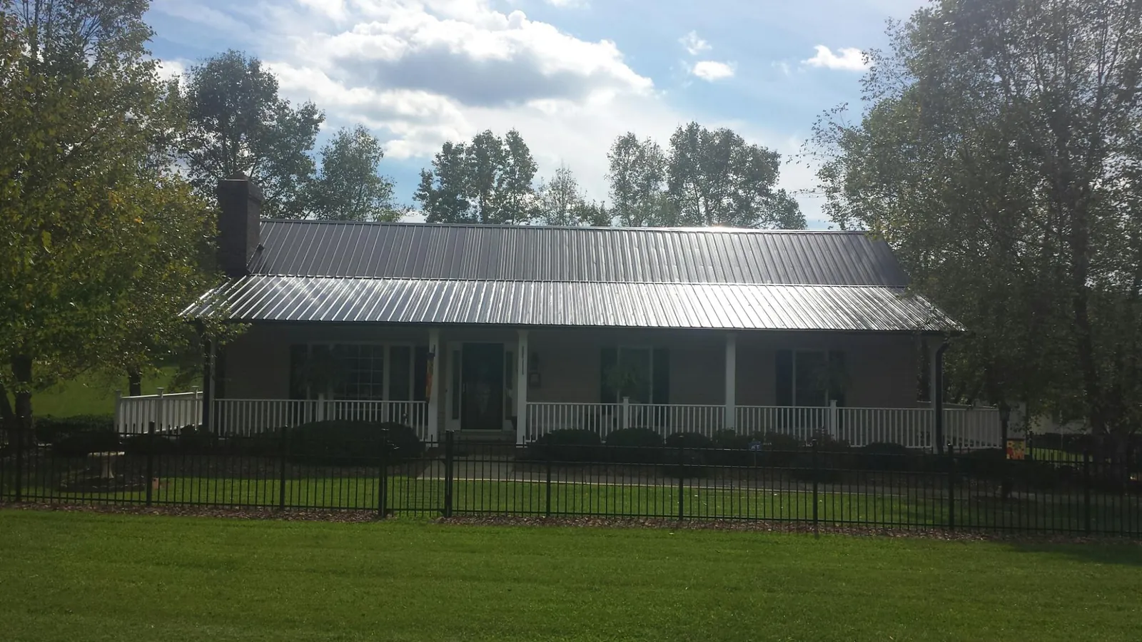 Gray metal roof on a brick ranch with a full width front porch — Gutter Guard Installation work by our crew in Irene